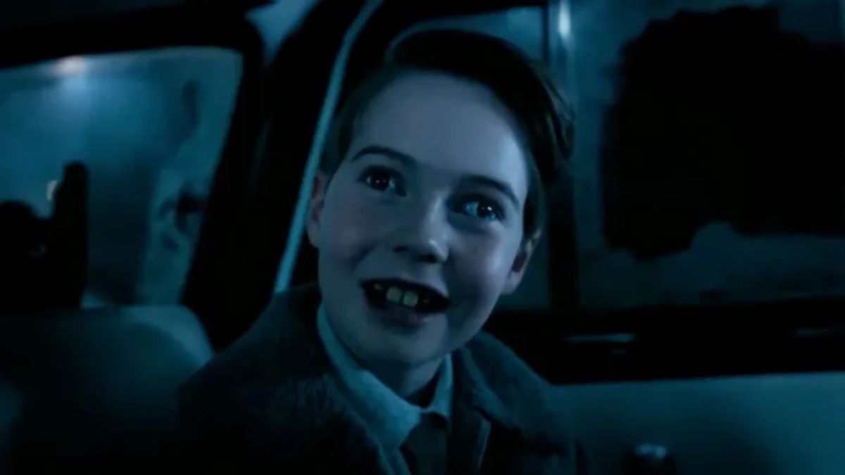 A young boy with a wide smile looking out from inside a car at night, from HBO Max's "IT: Welcome to Derry."
