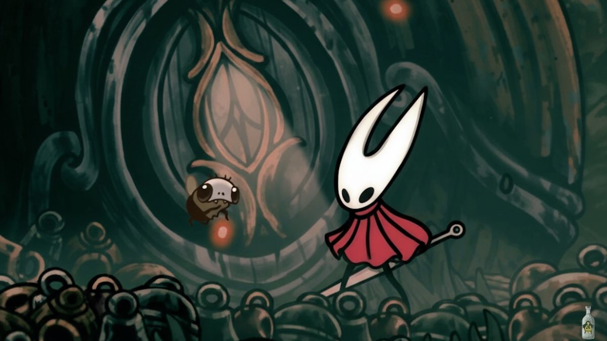 A close-up screenshot from Hollow Knight: Silksong showing the character Hornet standing next to a small, bug-like creature, Yarnaby in a dark, cave-like environment. The background features a large, ornate machine or structure.