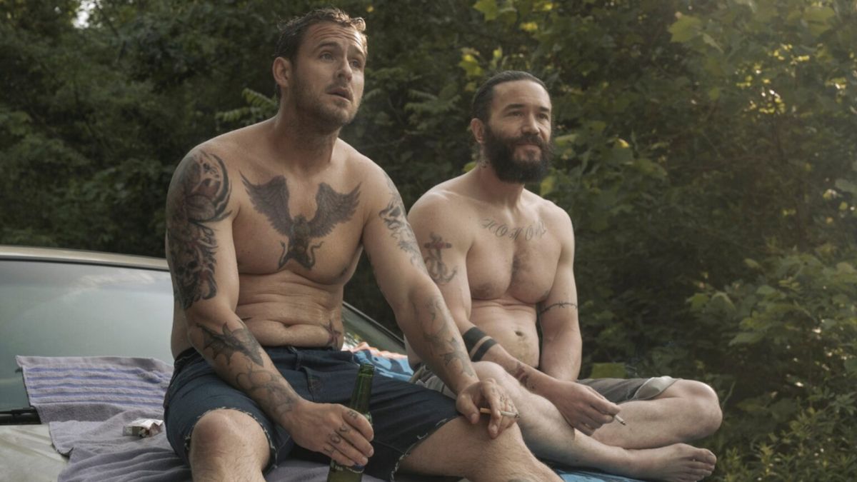 Shirtless Dark Hearts gang members Robbie and Cliff (Raúl Castillo), covered in tattoos, sitting on a car hood, contemplating their future in the intense crime drama Task.