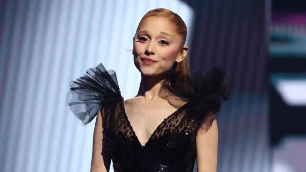 Ariana Grande, wearing a sophisticated black ruffled dress, is shown in a promotional shot for her return to television in American Horror Story Season 13.