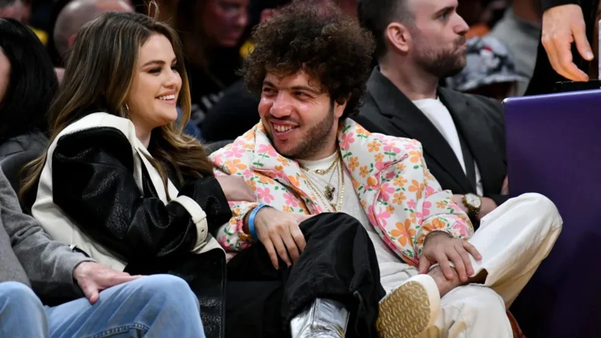 Selena Gomez and Benny Blanco laughing together while sitting courtside at a Los Angeles Lakers game in January 2024.