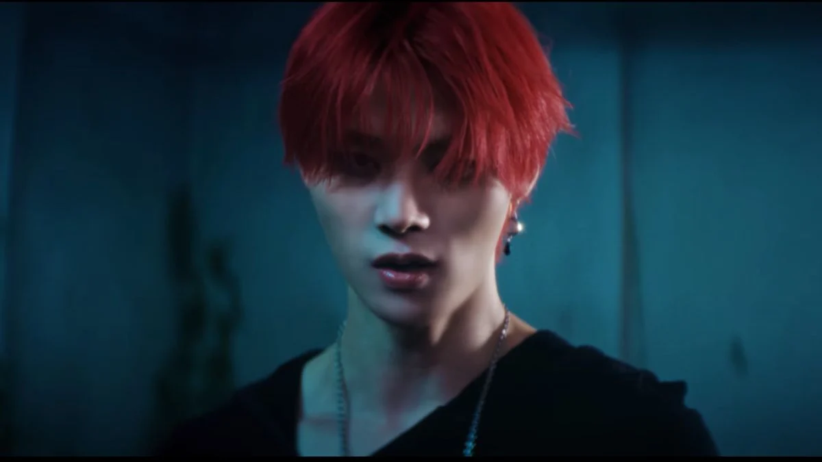 A close-up shot of an 8TURN member with bright red hair and an intense expression from the BRUISE highlight clip.