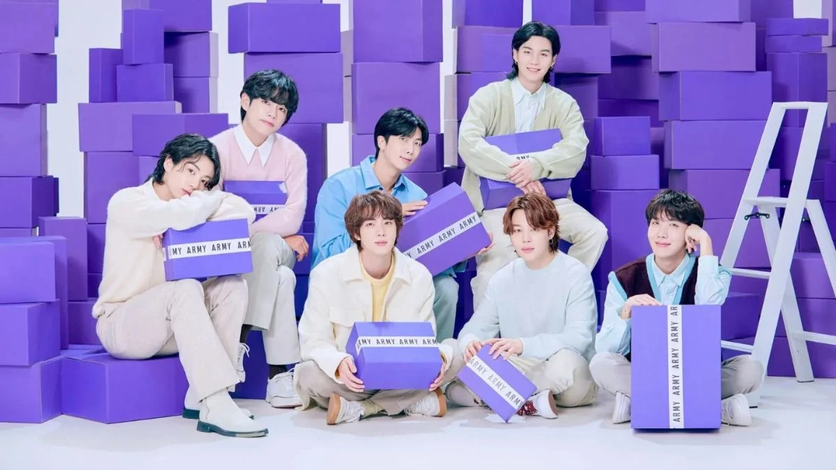 All seven members of BTS sitting among purple boxes to celebrate ARMY