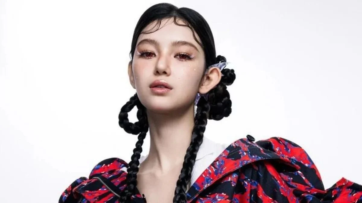 Danielle of NewJeans posing with a colorful red and black patterned jacket and intricate braided hair.