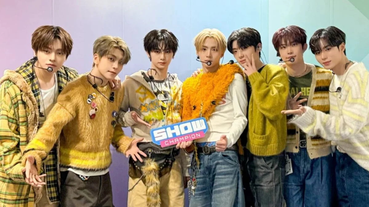 The eight members of rookie K-pop group ALPHA DRIVE ONE holding their first Show Champion trophy for Freak Alarm.