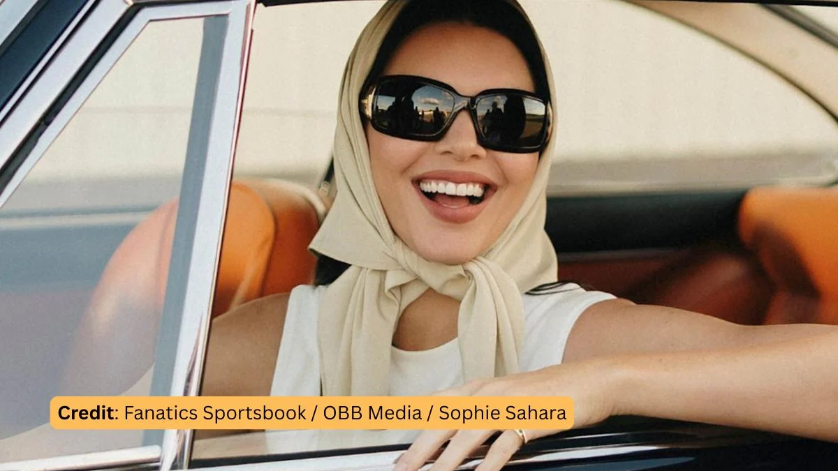 Kendall Jenner smiling in a vintage sports car while wearing a headscarf and sunglasses for her Fanatics Super Bowl ad.