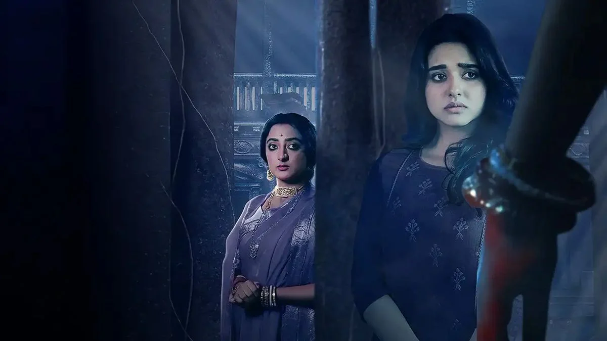 Sweta Mishra as Titli and another character standing in the shadows of a dark, atmospheric forest setting in Nishir Daak.