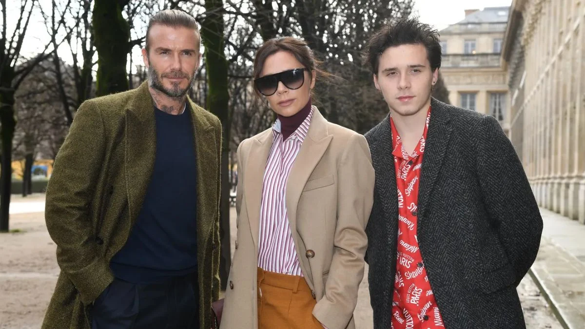 David Beckham, Victoria Beckham, and a young Brooklyn Beckham posing together at a public event.