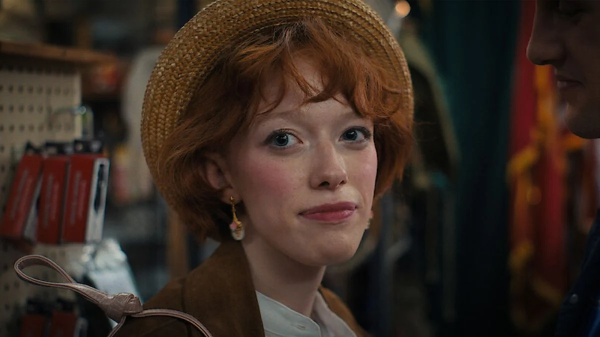 AmyBeth McNulty as Vickie in Stranger Things wearing a straw hat and brown jacket.