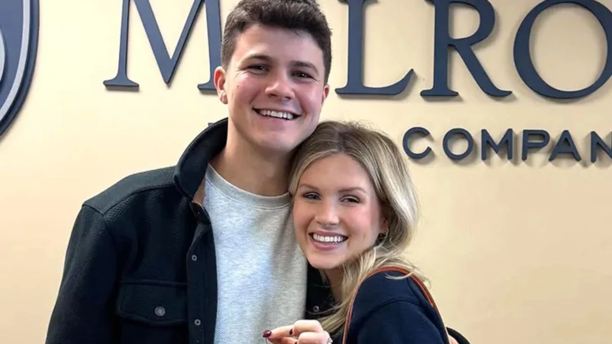 Travis Clark and Katie Bates Clark smiling together in front of a Melrose Company sign.