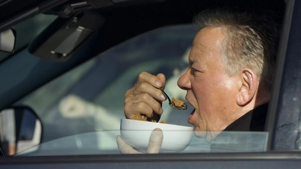 William Shatner eating a bowl of Kellogg's Raisin Bran behind the wheel of an SUV at a Los Angeles stoplight.