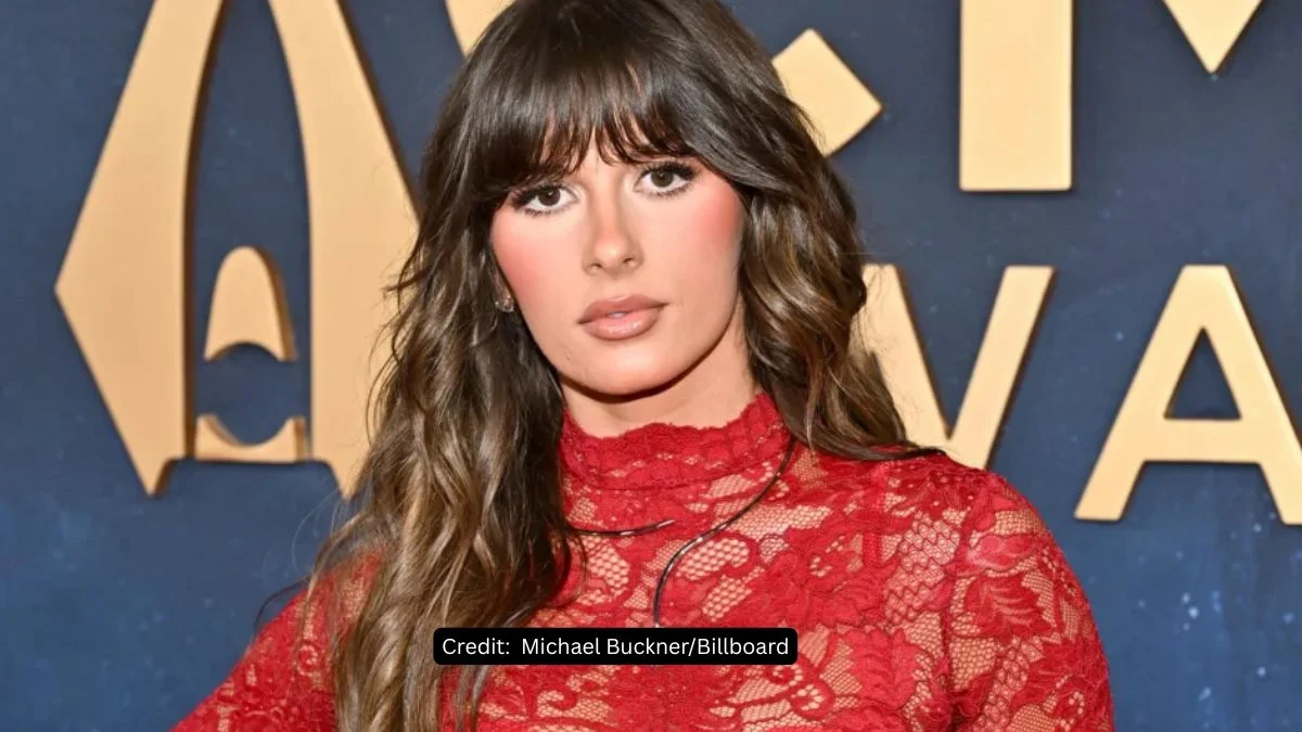 Singer Ella Langley posing on a red carpet in a red lace dress.