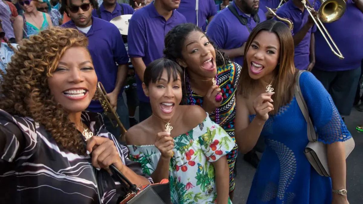The original Girls Trip cast Queen Latifah, Jada Pinkett Smith, Tiffany Haddish, and Regina Hall smiling together at a festival.