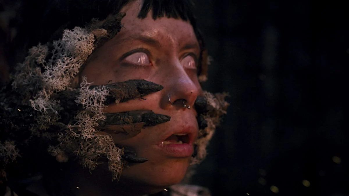 Close up of a woman with white eyes and tree branches growing out of her face in Heart of the Forest.