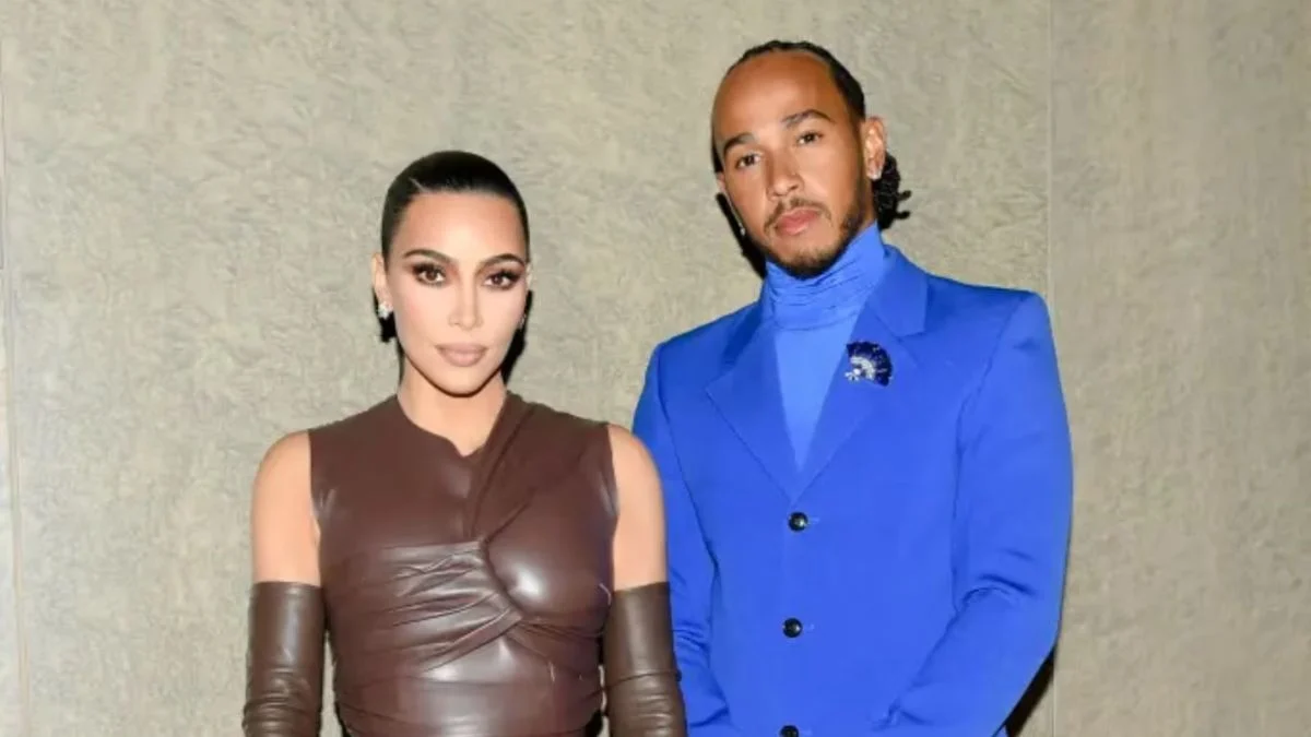 Kim Kardashian in a brown leather outfit standing next to Lewis Hamilton in a bright blue suit.