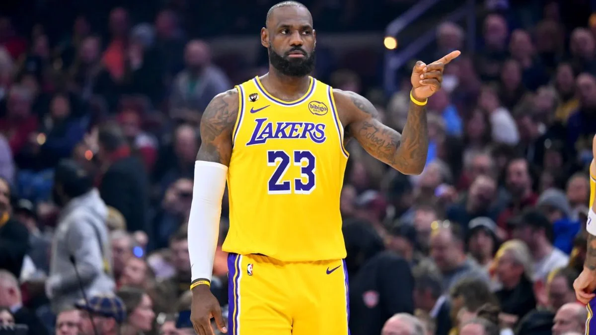LeBron James in a yellow Los Angeles Lakers jersey pointing during the game against the 76ers.