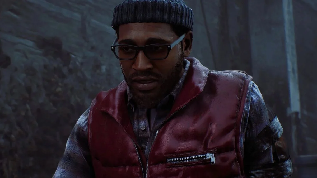 Close-up of Simon Ordell, the protagonist of Silent Hill Townfall, wearing glasses, a red vest, and a beanie in a dark, gritty environment.