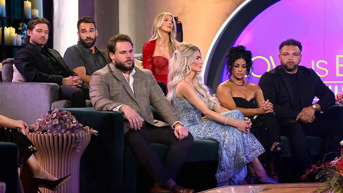 The Love Is Blind Season 10 cast sitting on sofas during the reunion special, featuring Jordan Faeth, Amber Morrison, and others in formal attire.