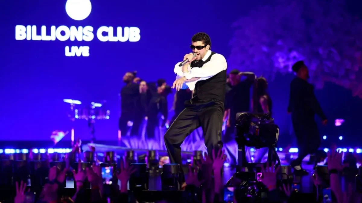 Bad Bunny singing into a microphone on a purple-lit stage with the Spotify Billions Club Live logo in the background.
