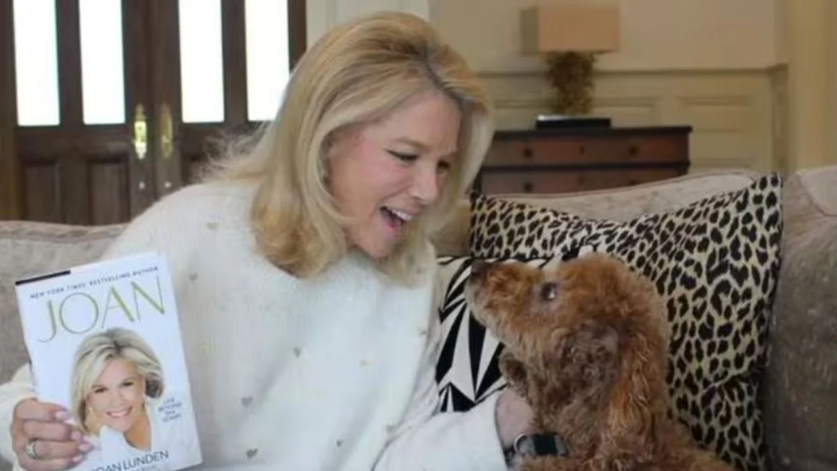Joan Lunden smiling on a sofa with her dog while holding her 2026 memoir "Joan: Life Beyond the Script."