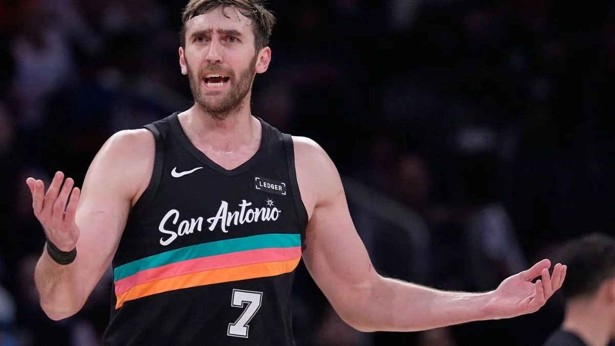 San Antonio Spurs center Luke Kornet looking frustrated with his hands spread open during an NBA game.