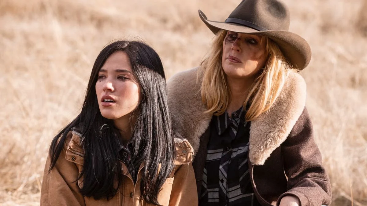 Monica Dutton and Beth Dutton sitting together in a field during a dramatic scene from the Yellowstone universe.