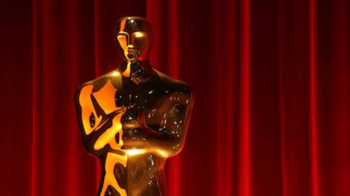 A golden Oscar statuette against a dramatic red curtain backdrop for the 98th Academy Awards.