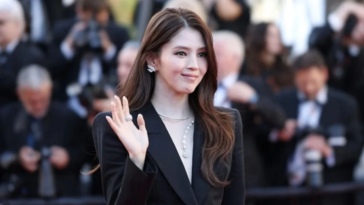 Han So-Hee waving at the 2026 Cannes Film Festival red carpet wearing a tailored black Blumarine blazer.