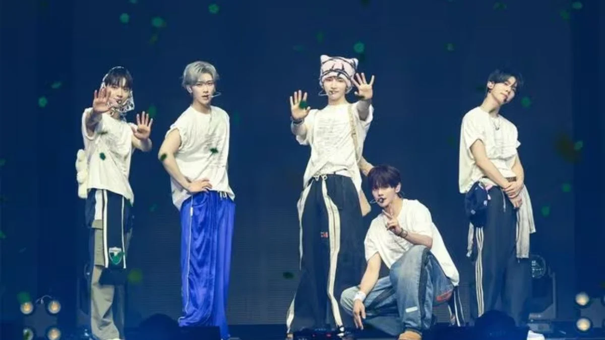 K-pop group AND2BLE posing together on stage in sporty casual t-shirts and jeans during the finale of their Seoul concert.