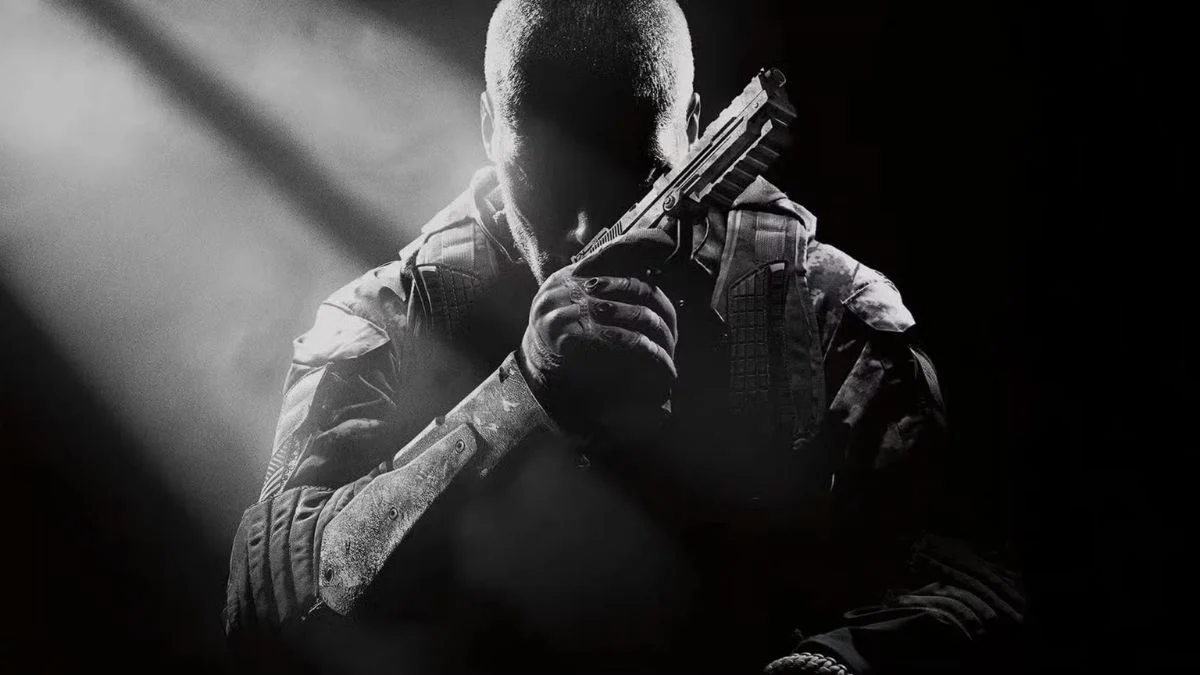 A dramatic black and white key art image of a soldier in military gear holding a handgun close to his face in a classic tactical pose against a dark background.