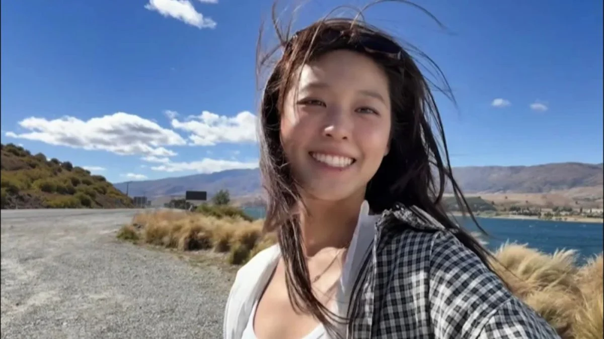 Former AOA member Seolhyun smiling in a casual outdoor selfie during her New Zealand road trip vlog under a blue sky.