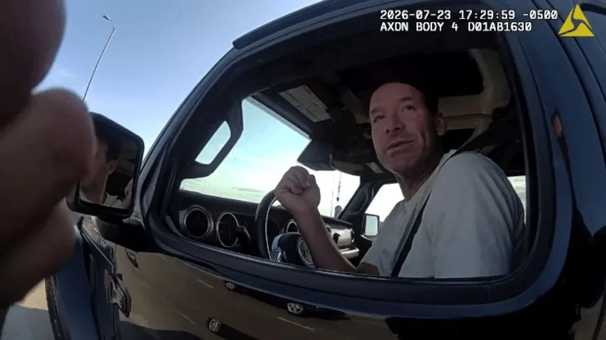 Axon bodycam footage screenshot showing former NFL star Tony Romo sitting in the driver's seat of a black vehicle, speaking out of the open window to a deputy during a traffic stop.