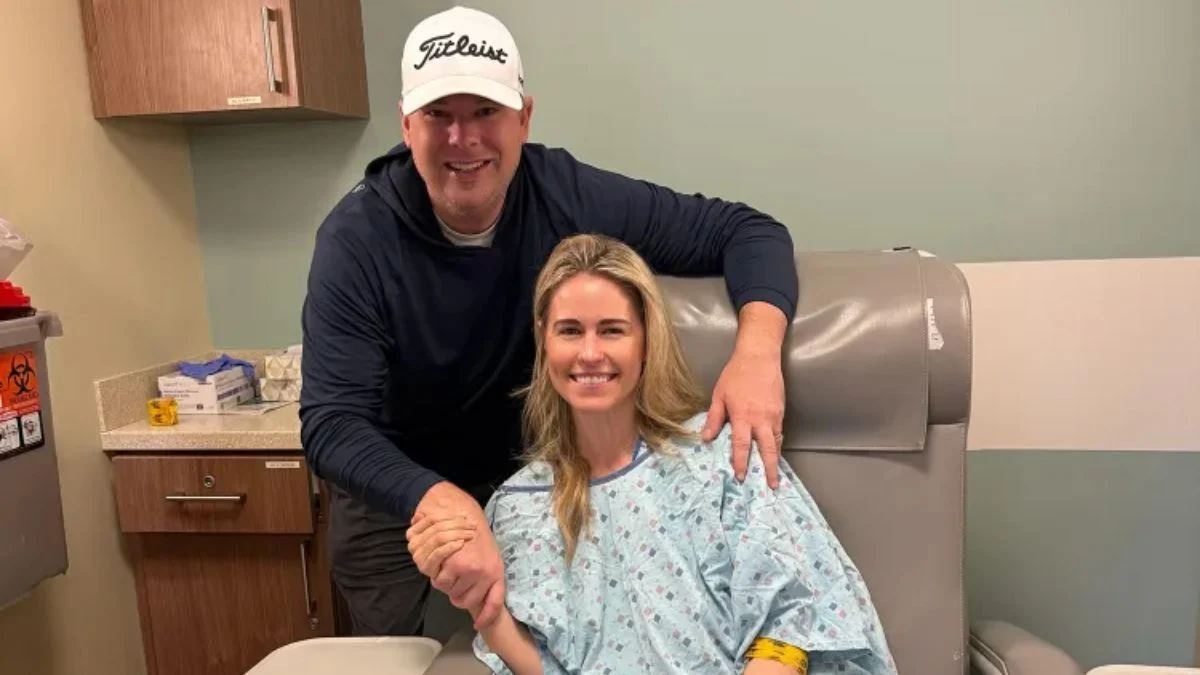 Country singer Jillian Cardarelli smiling in a hospital bed holding a teddy bear and holding hands with her husband Brian Parker during her breast cancer treatment.