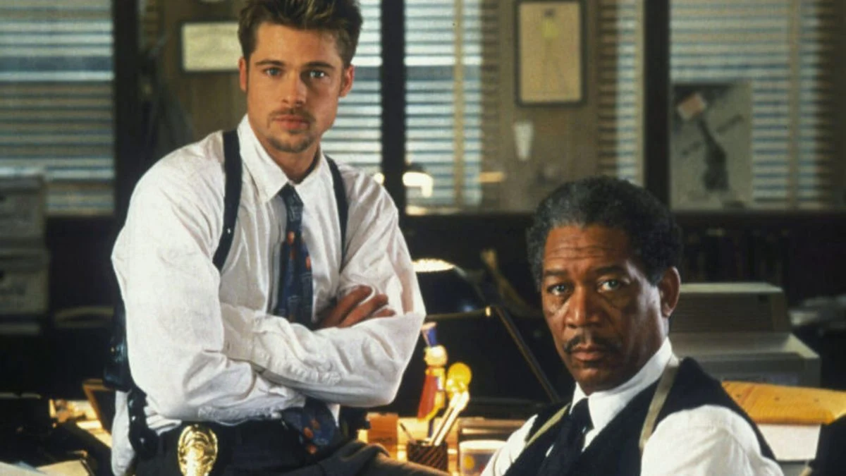 Detectives David Mills and William Somerset posing inside their busy, crowded police precinct office in the movie Se7en.