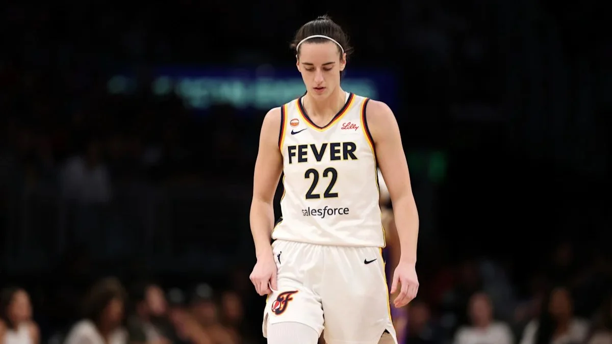 Caitlin Clark wearing her white Indiana Fever number 22 jersey looking down on the court during a game.
