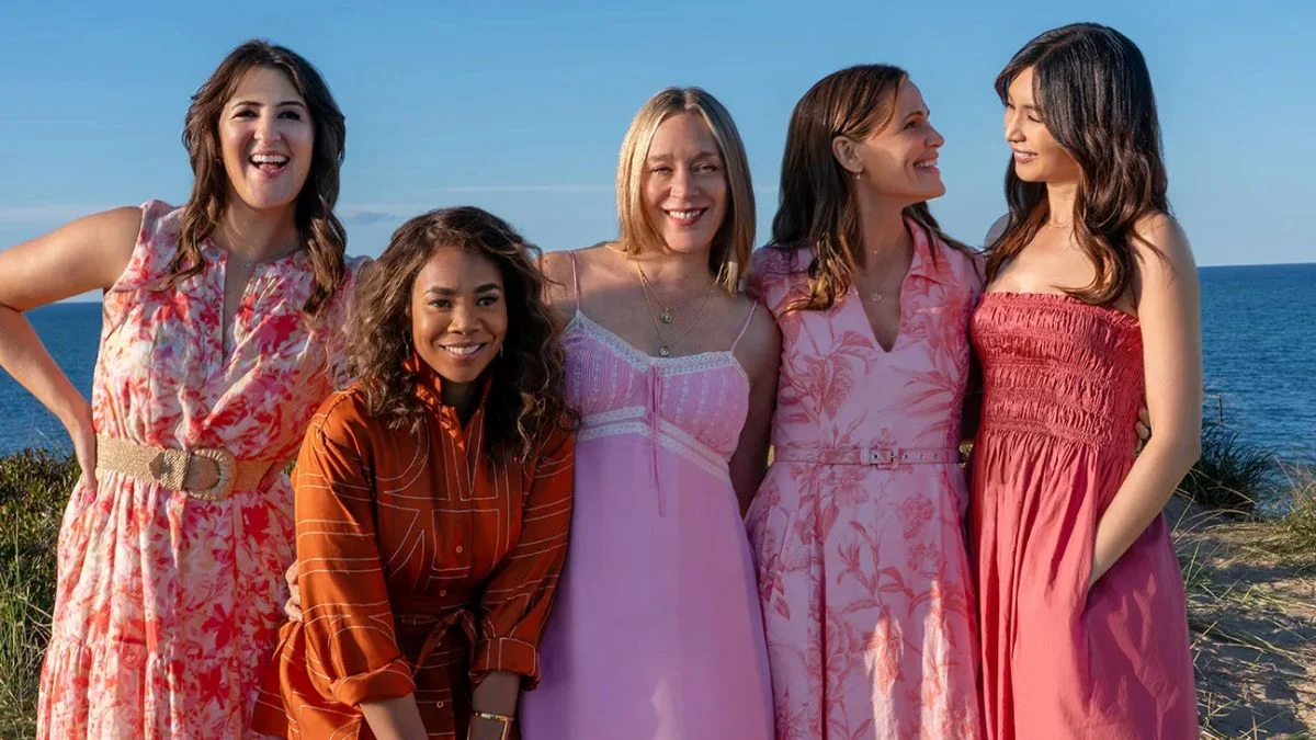 From left to right, D’Arcy Carden, Regina Hall, Chloë Sevigny, Jennifer Garner, and Gemma Chan smile and pose together outdoors on a sunny day with the ocean in the background in a scene from the Peacock miniseries The Five Star Weekend.