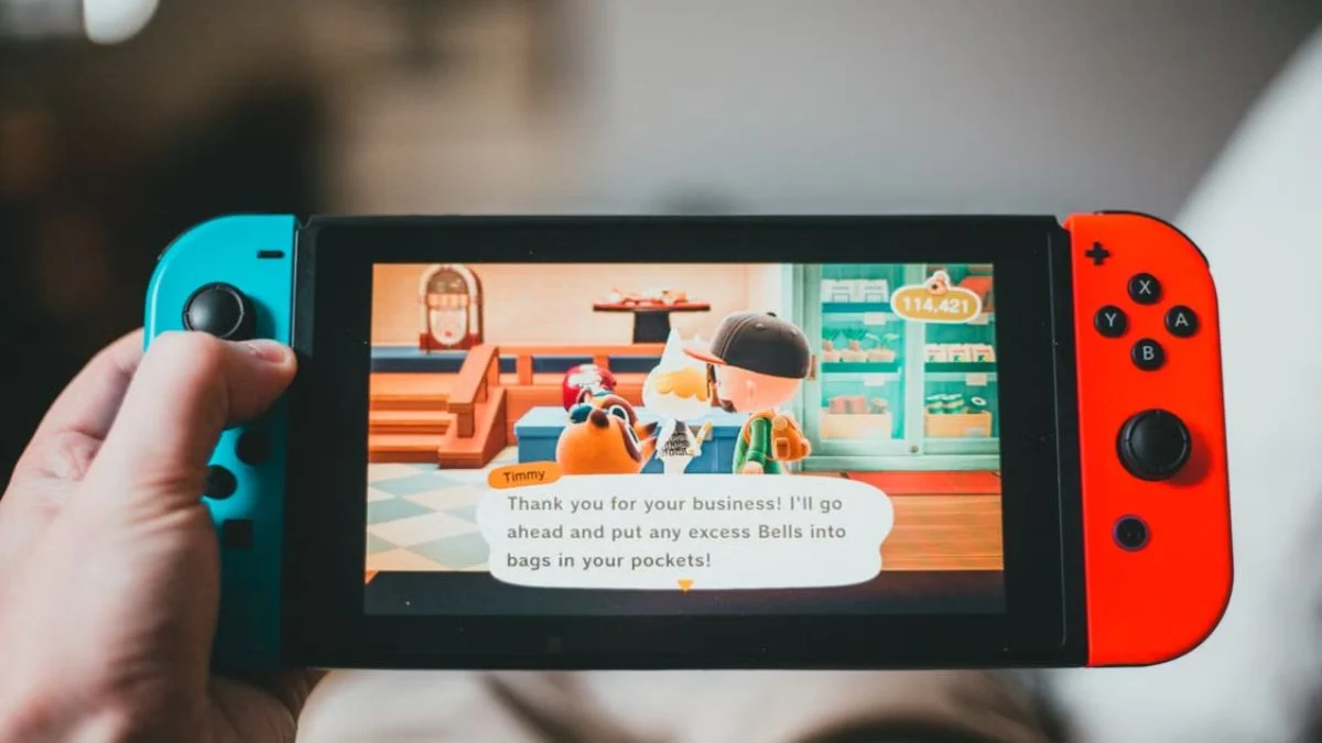 Close-up of hands holding a Nintendo Switch playing Animal Crossing: New Horizons in handheld mode.