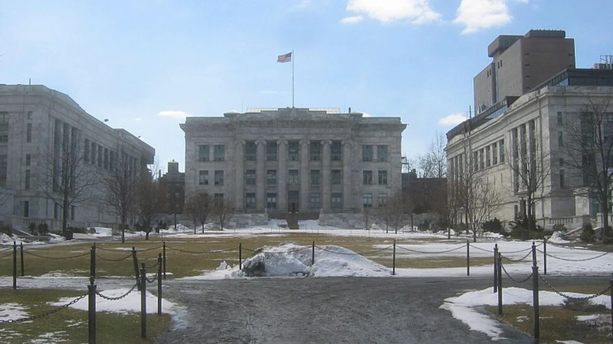 Exterior view of Harvard Medical School quadrangle and historic stone buildings on a clear day with snow patches on the grass.
