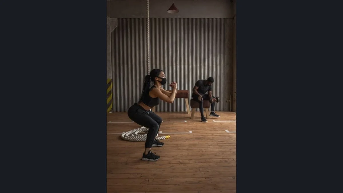 A woman performing bodyweight squats in an indoor workout space