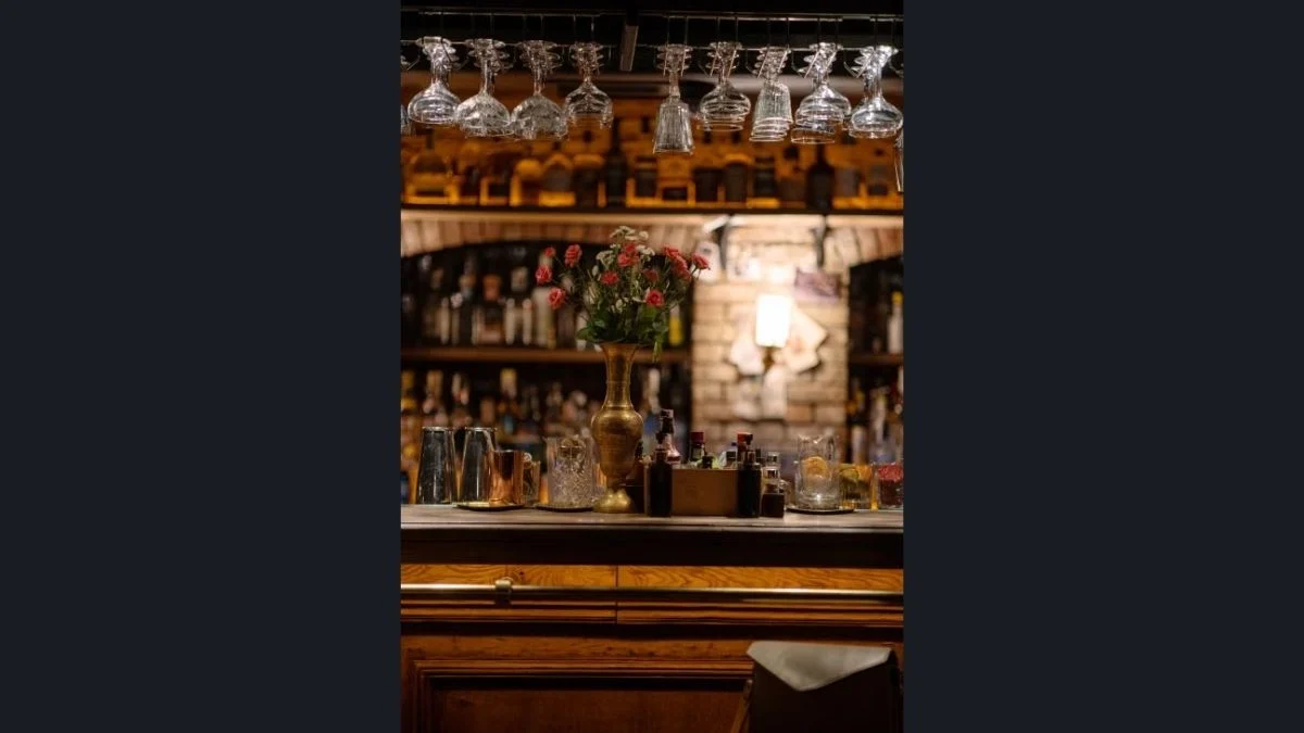 An elegant cocktail bar counter with glassware hanging overhead and flower decor