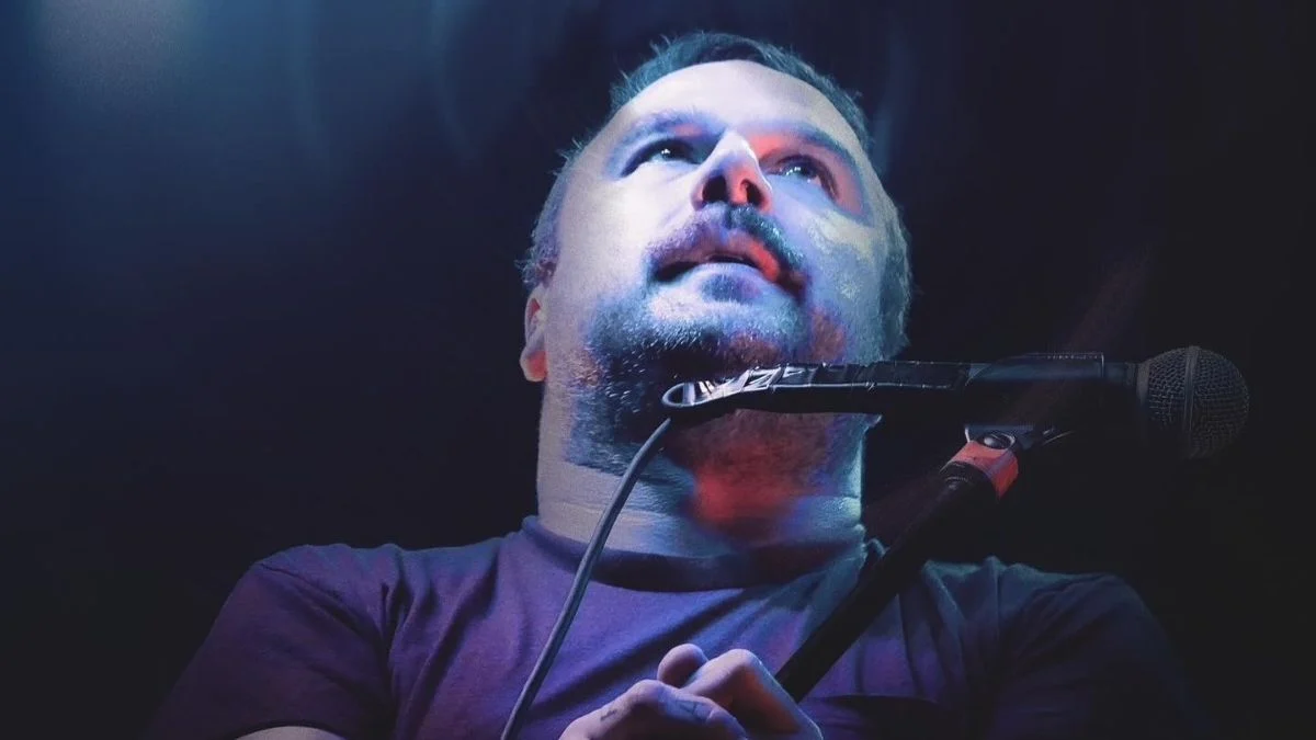 Max Bemis performing on stage with a microphone during a live concert