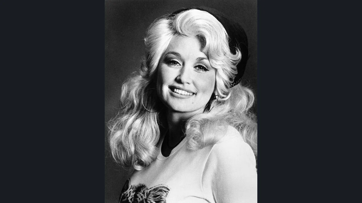 Black and white vintage portrait of country music icon Dolly Parton smiling with styled blonde hair.