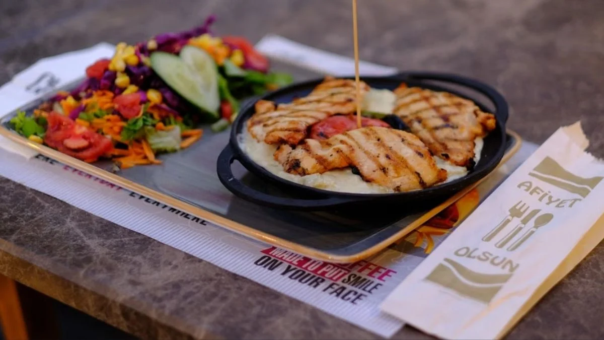 A restaurant meal plate featuring grilled chicken cutlets served alongside a fresh garden salad