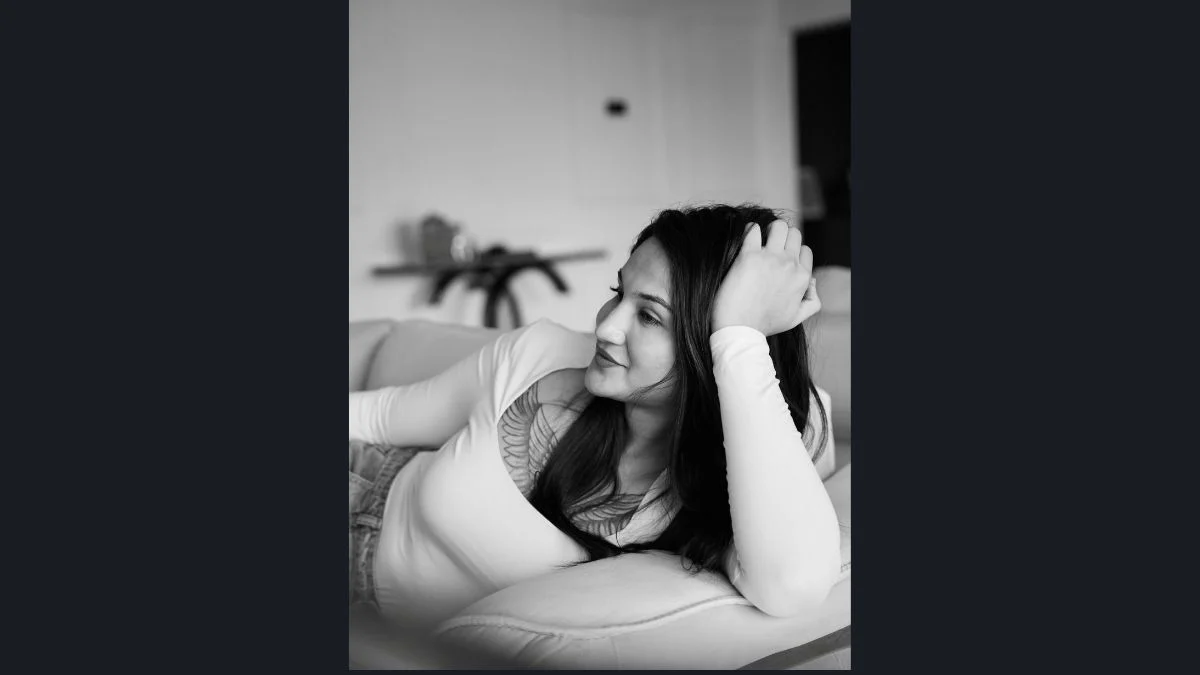 Black and white portrait of Anaya Bangar resting on a sofa with her hand near her hair