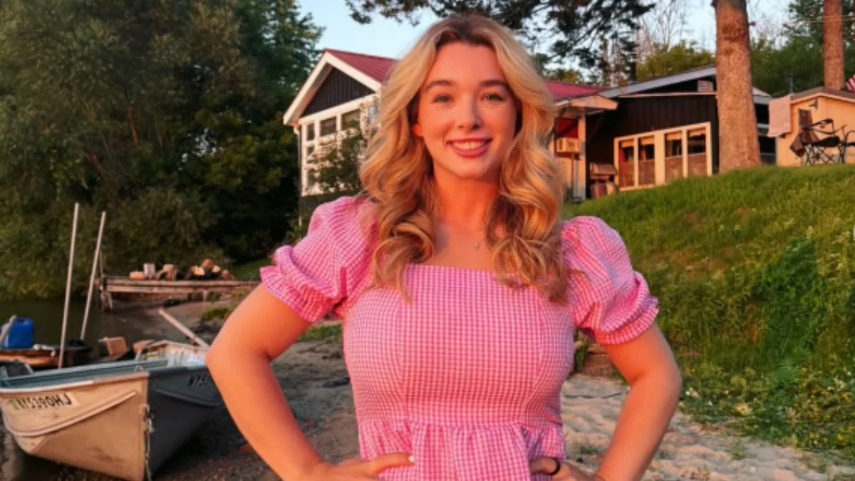TLC star Baylen Dupree-Dooley poses outdoors near a lake shoreline in a pink gingham puff-sleeve dress.