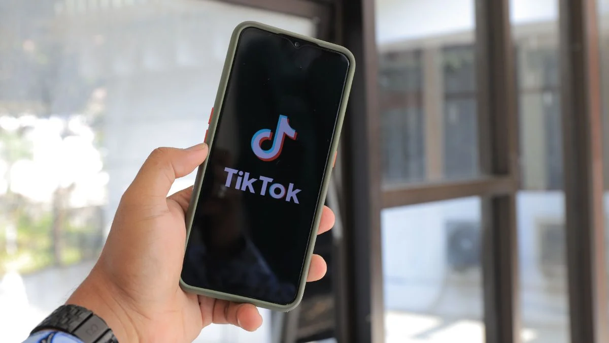 Person holding a smartphone displaying the TikTok app logo on the screen