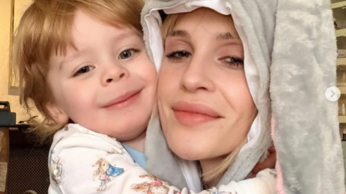 Kelly Osbourne wearing a bunny hood smiling alongside her young son Sidney.