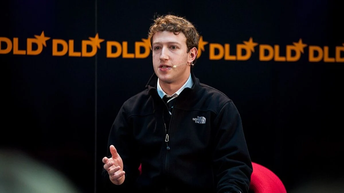 Mark Zuckerberg speaking on stage at a conference wearing a black jacket and microphone.