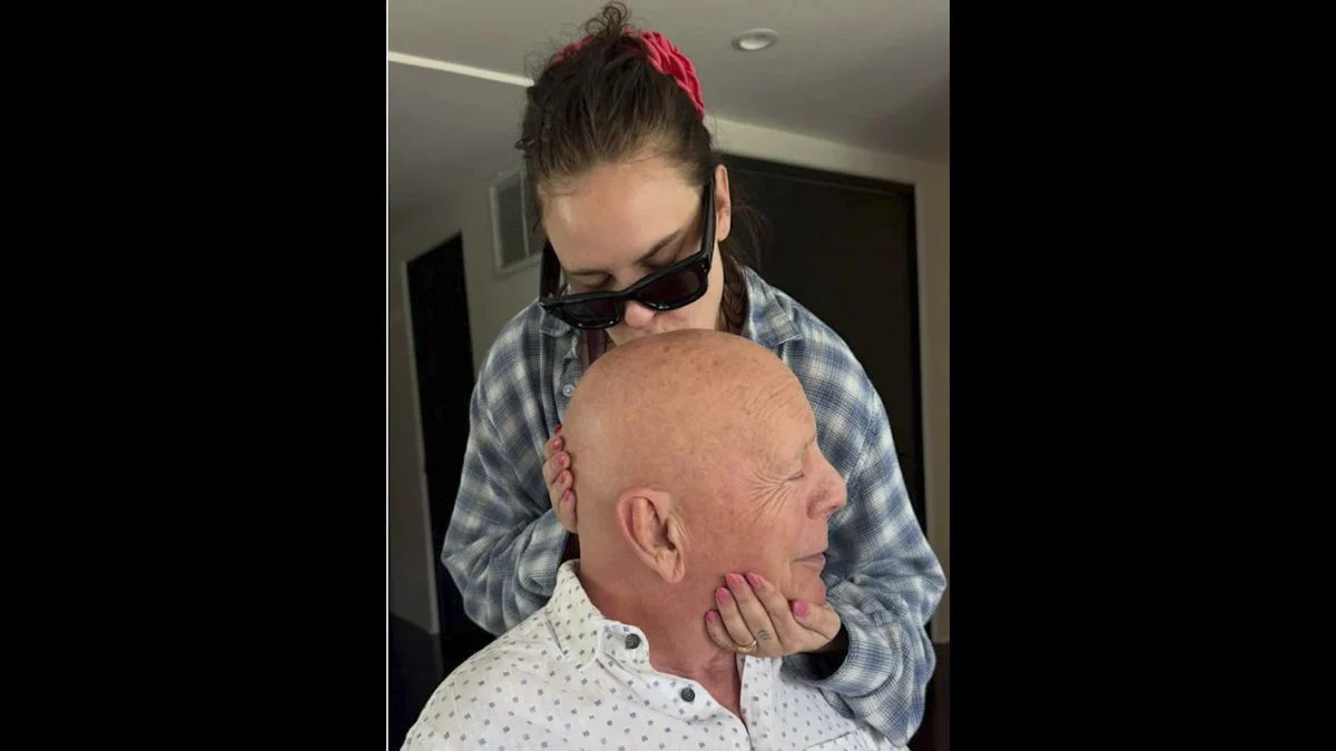 Tallulah Willis gently holding her father Bruce Willis' head and kissing him on the forehead in an intimate family photo.