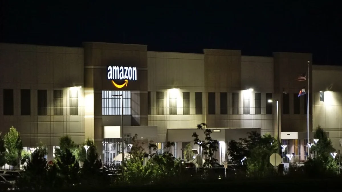 Exterior illuminated Amazon logistics facility building seen at night